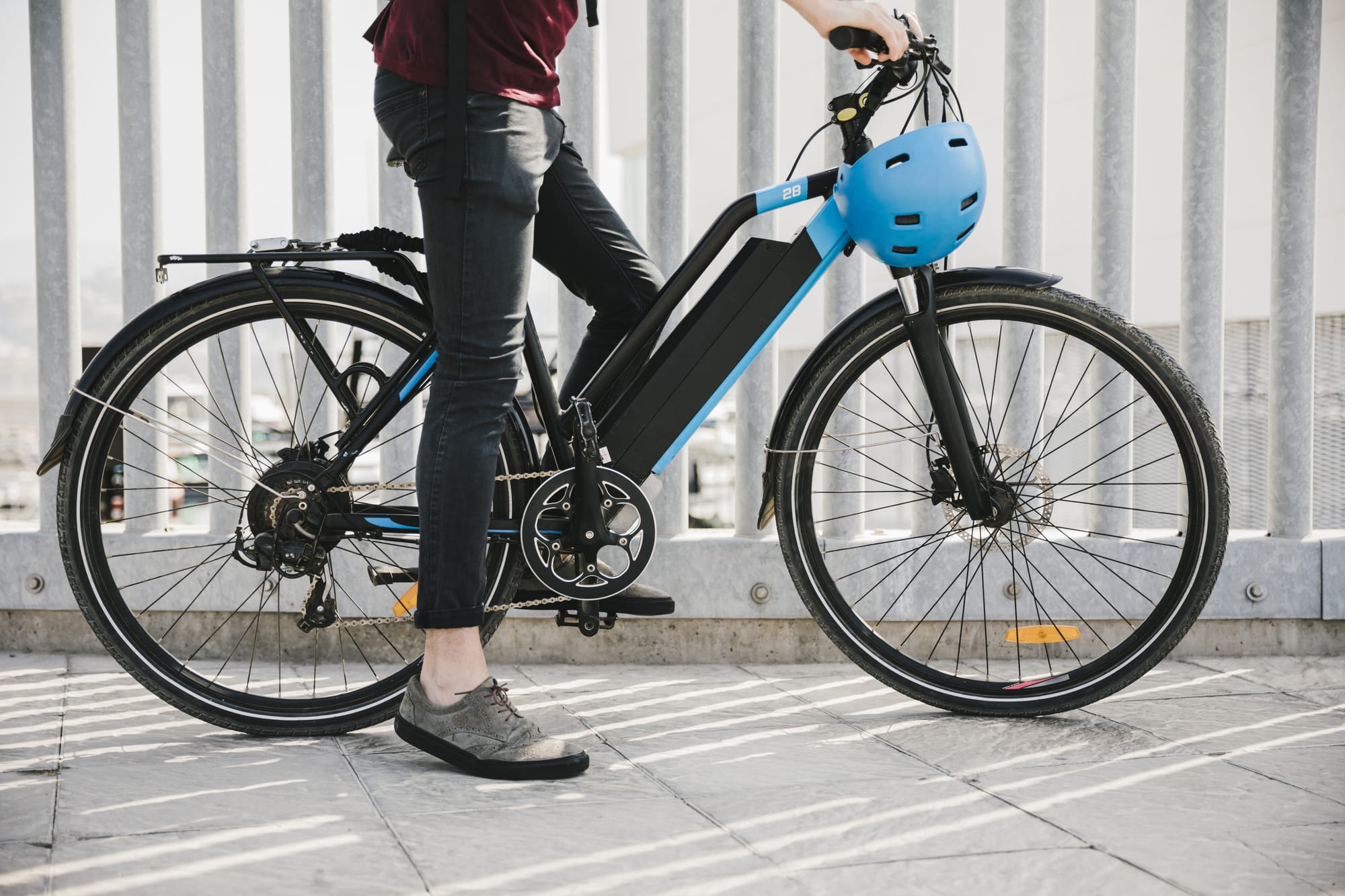 Person standing with an electric bicycle and helmet.